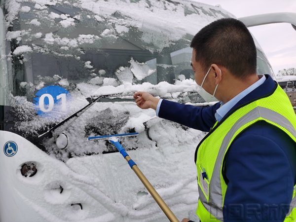 摆渡车司机正在清除车辆上的积雪。.jpg