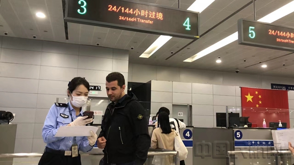 民警正在帮助旅客申请办理144小时过境边检手续-孙俊峰摄1
