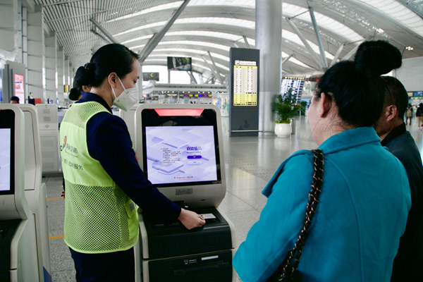 机场志愿者为旅客提供自助值机辅助服务