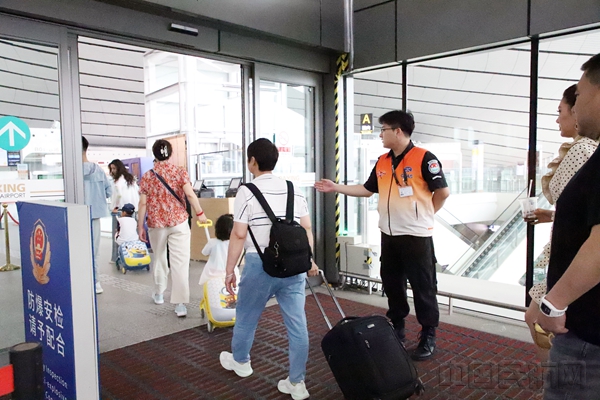 图说:安检员正在指引旅客通过防爆安全检查进入航站楼10