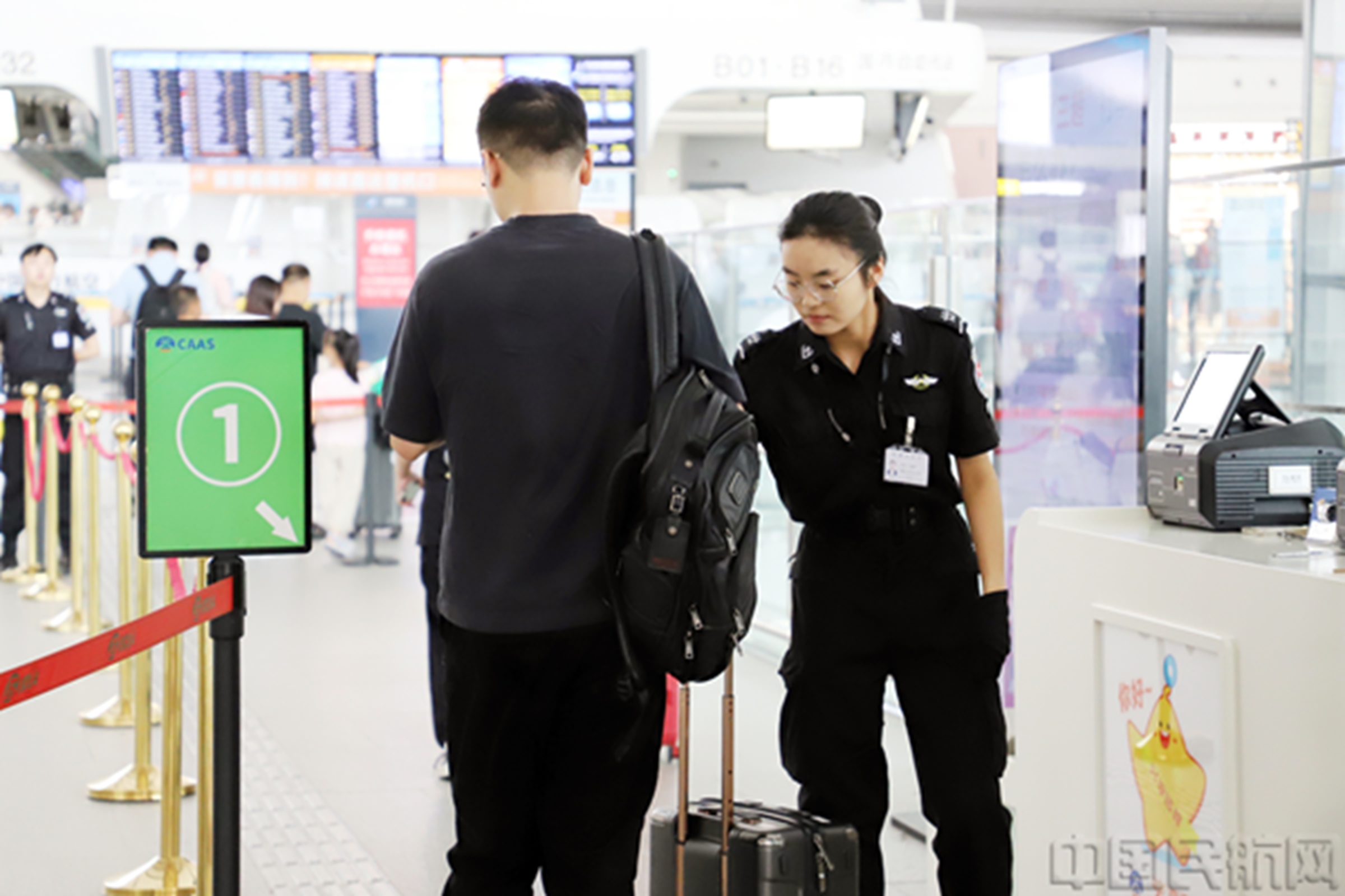 图说:安检员正在对进入航站楼的旅客进行防爆检查