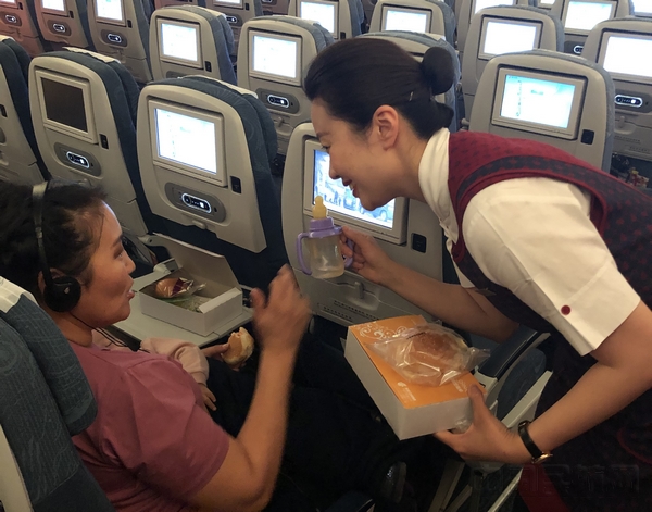 国航乘务员为婴儿和家属准备温水及餐食。摄影朱晋.jpg