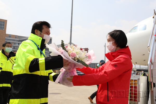nEO_IMG_东航机务狄海国在机坪手捧花束,迎接援鄂归来的妻子奚欢-东航供图