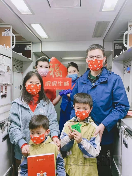 nEO_IMG_“虹桥-三亚”航班乘务组身着礼服,客舱经理钱丽敏和乘务员庄莉颖为旅客送上东航春联和福袋红包