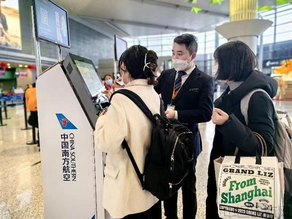 上海虹桥机场,南航工作人员正在引导旅客使用自助值机设备打印登机牌。柴媛 摄