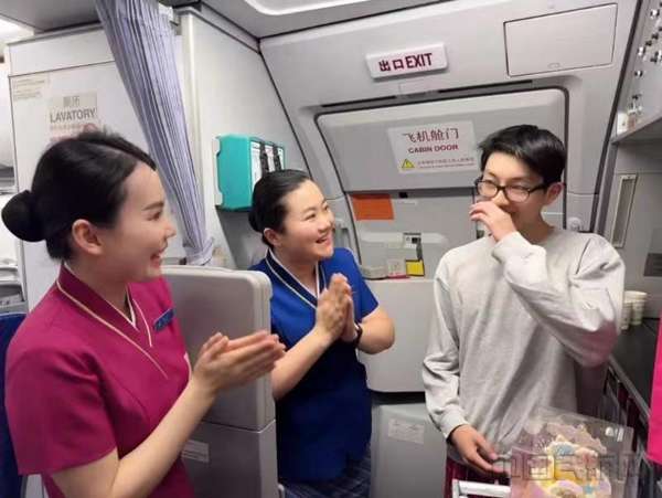 当CZ8310航班进入巡航阶段,乘务小姐姐们手捧蛋糕,唱着生日祝福歌,代表家人真诚地祝福小罗18岁生日快乐。何梦静 摄10