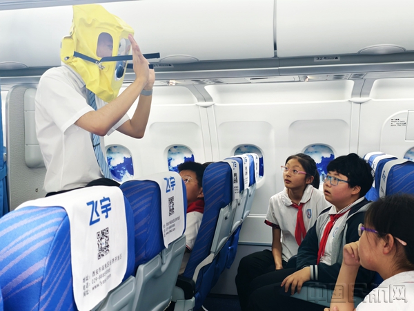乘务员向同学们展示如何佩戴放烟雾面罩,讲解客舱起火冒烟时的自救方法。潘水花 摄1